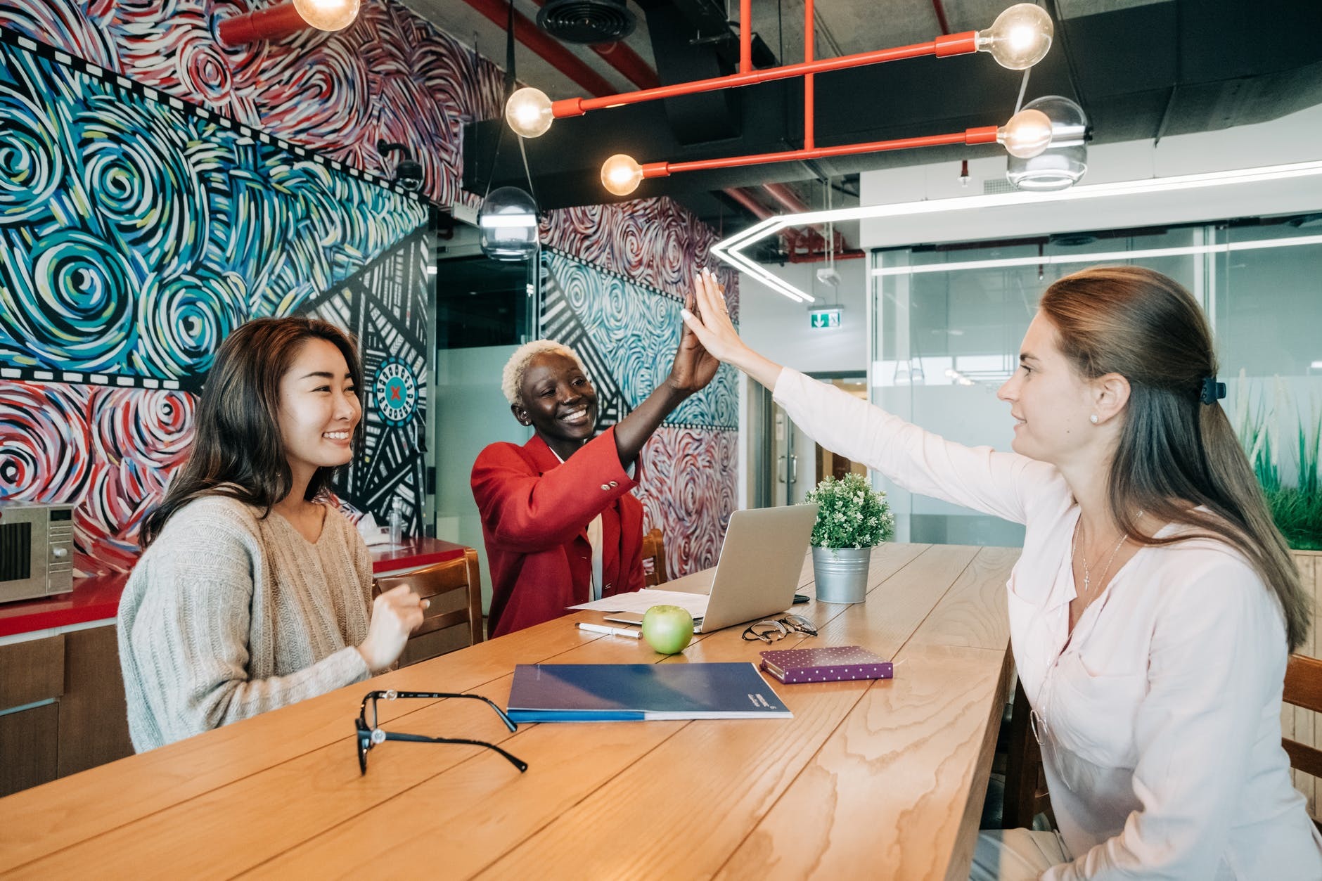 happy diverse female coworkers giving high five after successful deal